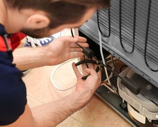 Técnico da Veralice Refrigeração ajustando fios e compressor em conserto de geladeira em Curitiba.