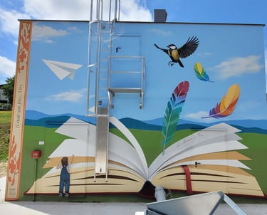 Fresque sur façade ext., plume écrivant sur un livre ouvert, un enfant et oiseau sur paysage épuré.