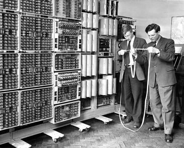 two men in suits and ties standing in front of a wall of many different types