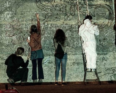 Group of people drawing on a projected wall, collective art workshop led by Poliops.