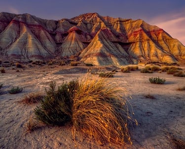Formación rocosa erosionada con capas de colores rojizos y blancos bajo la luz del atardecer