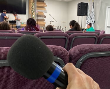 a microphone in a room with people sitting in chairs at church participating in worship warriors