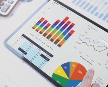 a person holding a tablet computer and pointing at a chart of graphs