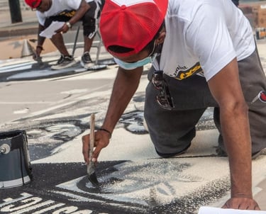 An image of two artists working on a justice mural.