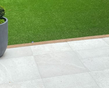 A family garden. The grass is green and there are lots of trees surrounding the lawn.