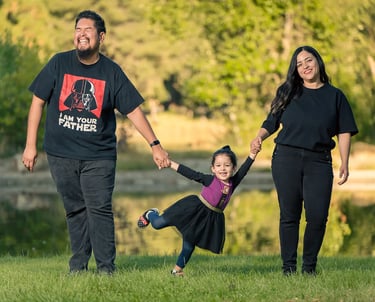 family photoshoot of a man and woman holding hands and holding kid by her hands