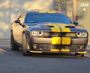 Custom automotive vinyl job: Yellow racing stripes applied from front to back on a black Dodge Chall