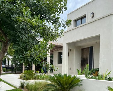a house with a white wall and a tree in the background
