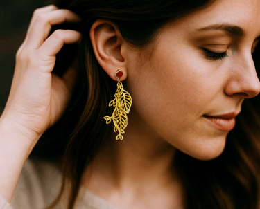 a woman wearing a gold leaf earrings that have plastic posts for sensitive