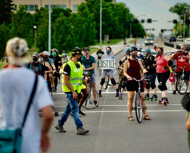 Bikers stopped on a road, with one holding a sign that reads "Justice"