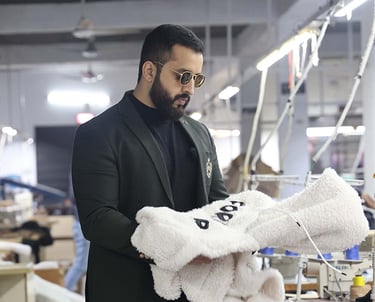 a man in a suit jacket is holding a sherpa fleece hoodie in a manufacturing factory
