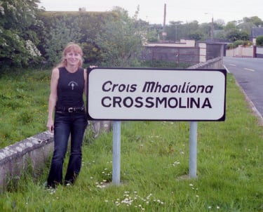 Annie of Crossmolina Band standing next to the welcome sign, County Mayo, Republic of Ireland.