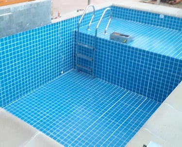 a pool with a blue tiled pool and a wooden deck