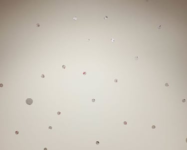 Multiple silver dot decals scattered in a playful pattern on a white background mural.