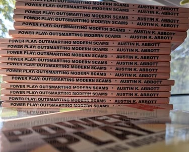Stack of books titled Power Play: Outsmarting Modern Scams by Austin K. Abbott, arranged with their spines facing outward