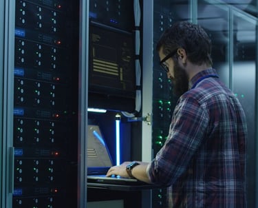 a man in a plaid shirt is standing in front of a server rack