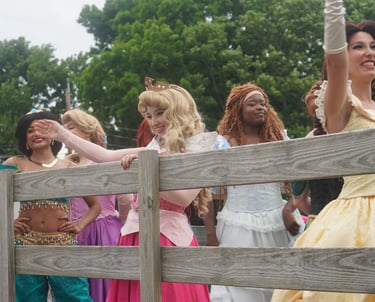 Princesses wave at guests during a parade