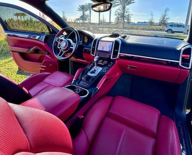 Interior of a luxury SUV with red leather seats and black trim, freshly detailed and parked under clear Florida skies
