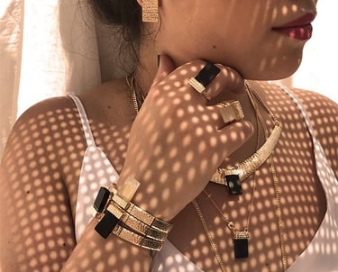uma mulher usando um mix de colares e de pulseiras pratas e douradas. todas as joias tem um cristal 