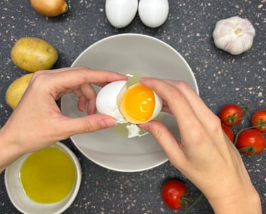 Hands breaking an egg with potatoes, onions and eggs for a Spanish cooking class in Tallinn, Estonia