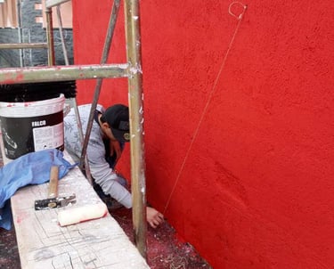 Poliops preparing the red base of a large urban mural, first stage of the exterior painting.