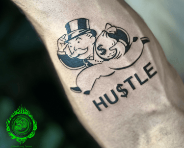 a tattoo on forearm with monopoly character holding a bag of money and "hustle" lettering.