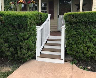 Front porch steps in composite deck boards and vinyl posts and railings installed by Golden Rule 