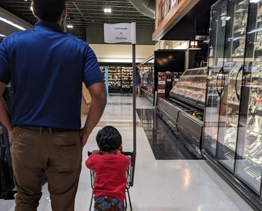 A child pushing a shopping cart that reads customer in training