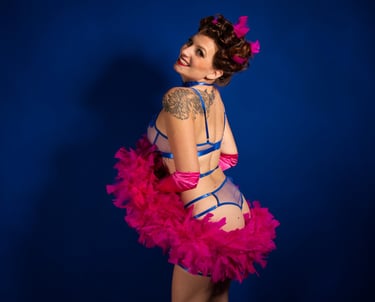 Pin up joyeuse en lingerie bleue avec un boa en plumes rose, qui sourie.