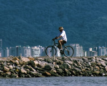 Homem andando sobre enroncamento do rio juqueriquerê com prédios do centro de caraguá ao fundo