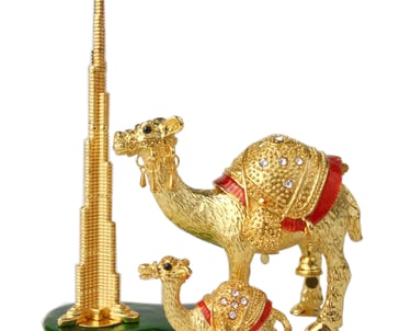 a gold colored camelia figurine of a camel in front of a tall