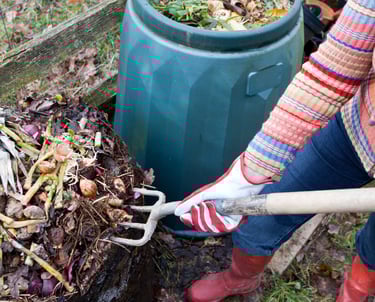 a woman turning over the compost pile