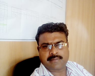 a man with glasses and a mustache sitting in front of a white board