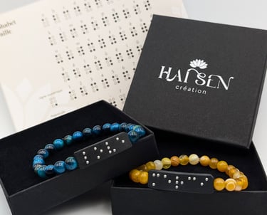 Bracelets perles avec plaques en braille, dans un écrin noire accompagné d'un alphabet braille.