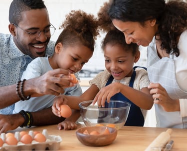 a family breaking eggs as they prepare food together