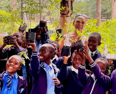 Smiling school children surrounding teacher and all holding up small trees