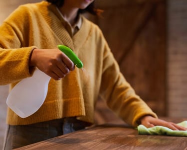 a woman is cleaning a table with a green cloth