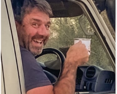 Herve Fritz laughing whilst driving and drinking coffee