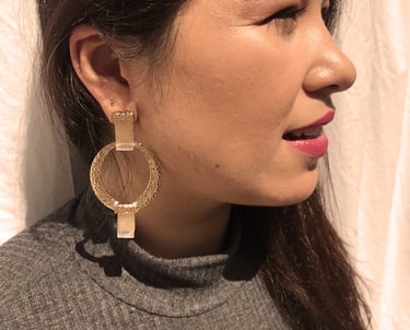 uma mulher com grandes brincos de argola de ouro com dois cristais nas extremidades