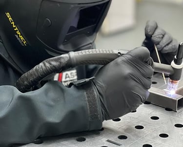 a person in a helmet and gloves is welding a piece of aluminium