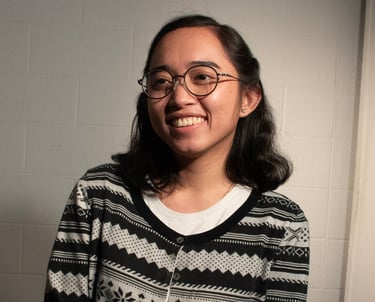Portrait of Fatima Fabillar, smiling and wearing a patterned cardigan against a neutral background