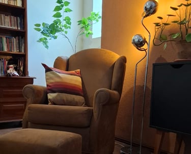 Poltrona confortável com almofada listrada e iluminação suave ao fundo, em espaço acolhedor preparad