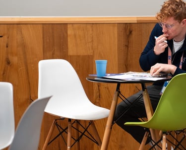 Journalist Przemysław "Przemek" Żuk sitzt an einem Tisch. Er denkt nach und schreibt handschriftliche Notizen.
