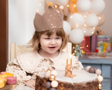 mala djevojčica sjedi za stolom i puše svijeće na torti