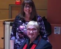 a woman sitting at a table with a book signing