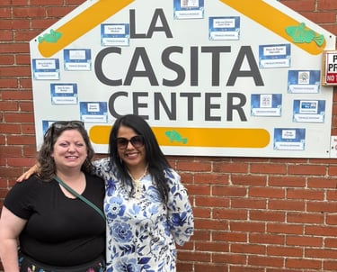 Two women standing in front of the La Casita Center building signage