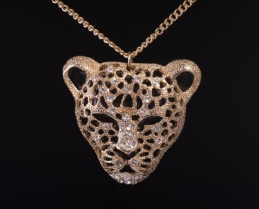 Picture of a Leopard's head shaped pendent on a dark background.