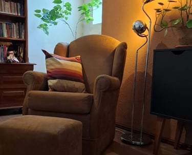 Poltrona confortável com almofada listrada e iluminação suave ao fundo, em espaço acolhedor preparad