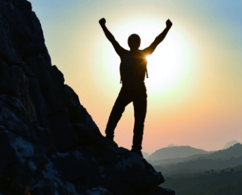 a person standing on a rock formation with a sun setting in the background