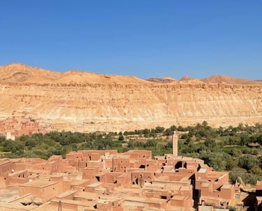 earthen village in the Ounila valley (Morocco), with mosque, fields and mountains in the background
